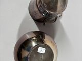 two silver vases on a white table with labels on them