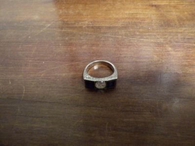 une bague en argent posée sur une table en bois, sur laquelle se trouve une bague noire