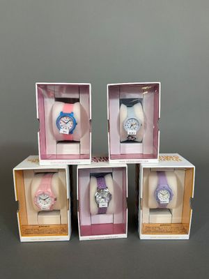 trois boîtes contenant chacune quatre montres différentes, posées sur une table