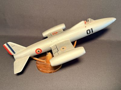 un petit avion en bois posé sur un socle en bois