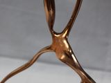gold metal sculpture of a person holding a flower on a white surface