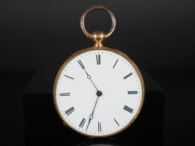 une image représentant une montre de poche en or posée sur une surface noire