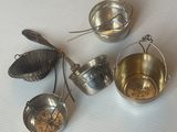trois casseroles en métal et une passoire sont posées sur une table