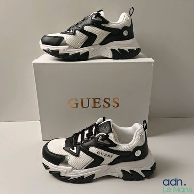 une paire de chaussures noires et blanches posée sur une boîte blanche