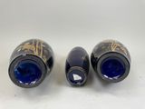 two blue vases with gold designs on them sitting on a white surface