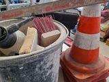 orange and white traffic cone sitting on top of a table next to a trash can
