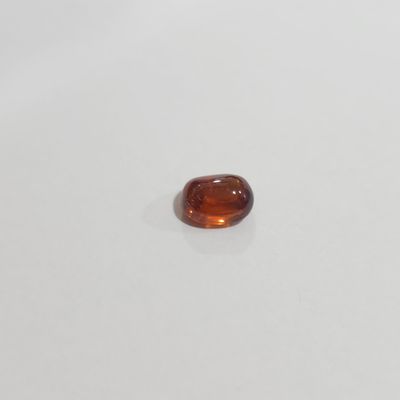 an oval shaped orange sapphire stone on a white surface