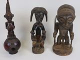 Trois figurines africaines sculptées sont assises les unes à côté des autres