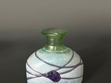 a green glass vase with a purple ribbon around it