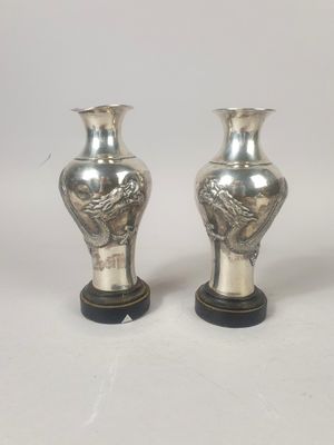 une paire de vases en argent posés sur un socle en bois