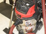 a vacuum that is sitting on the floor with a red hose
