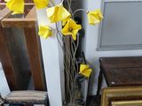 un vase contenant des fleurs jaunes, posé par terre