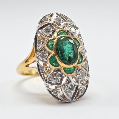 gros plan d'une bague avec une pierre verte entourée de diamants