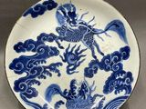blue and white plate with a dragon and clouds on it