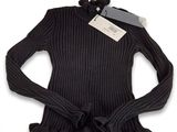 Le pull est noir, avec des volants et une étiquette.