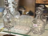 bottles and glasses are on a glass shelf in a store