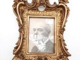 une photo d'un homme en costume et nœud papillon, dans un cadre doré