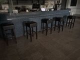 quatre tabourets devant un bar, avec un ordinateur portable posé sur le comptoir