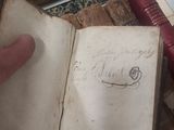 a hand that is holding an open book on a table