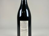 a bottle of black wine sitting on top of a white table