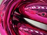 purple sculpture of a knot made of shiny metal on a white surface