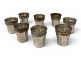 six silver shot glasses sitting on top of each other on a white surface