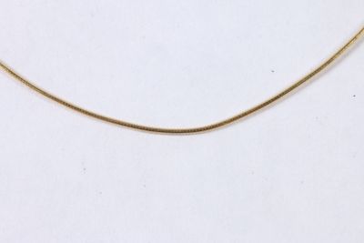 gros plan d'un collier en or sur une surface blanche