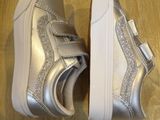 silver glittered shoes with bows on them on a wooden floor