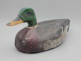un gros plan d'un canard en bois posé sur une surface blanche