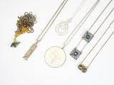 de nombreux colliers et une pièce de monnaie posés sur une surface blanche