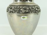 un vase en argent orné de fleurs, posé sur une table