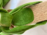 someone is wearing a pair of green shoes with a knot on the side