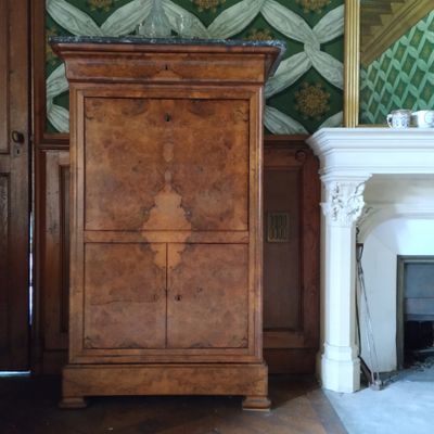 une grande armoire placée dans un coin d'une pièce dotée d'une cheminée