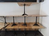 three wooden tables with black legs and a chalk board on the wall