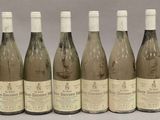 six bouteilles de vin sont alignées sur une table