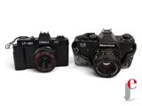 two cameras sitting next to each other on a white surface