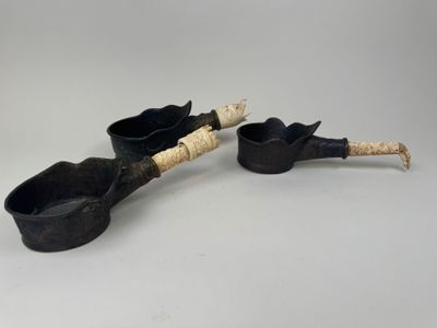 une paire de casseroles et de cuillères noires posées sur une table blanche