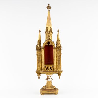 a gold - plated clock with a red glass in front of it