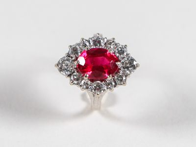 Gros plan sur une bague sertie d'un rubis et de diamants, posée sur une surface blanche