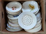 many plates and bowls in a box with a strainer