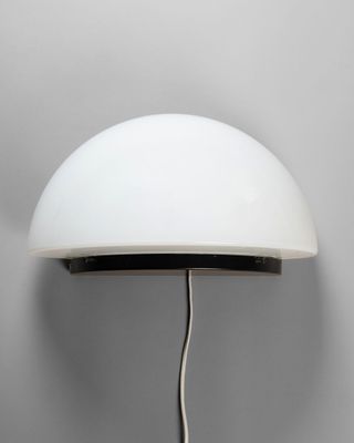 un gros plan d'une lampe murale avec un abat-jour blanc