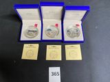three silver coins are in a blue box with a price tag