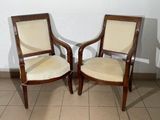pair of wooden chairs with beige upholstered seats in a room