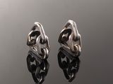 a pair of silver earrings sitting on top of a black surface