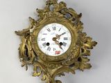 a gold clock on a white wall with a white background