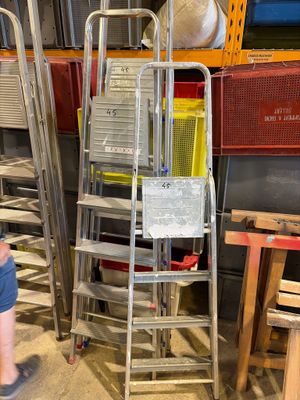 un homme debout à côté d'une pile d'échelles dans un entrepôt