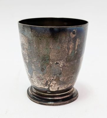 une coupe en argent posée sur un socle, sur une surface blanche