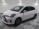 the white toyota yaris is parked in a large room