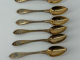 six spoons are lined up in a row on a white surface