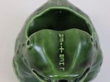 a green frog that is sitting on a white surface